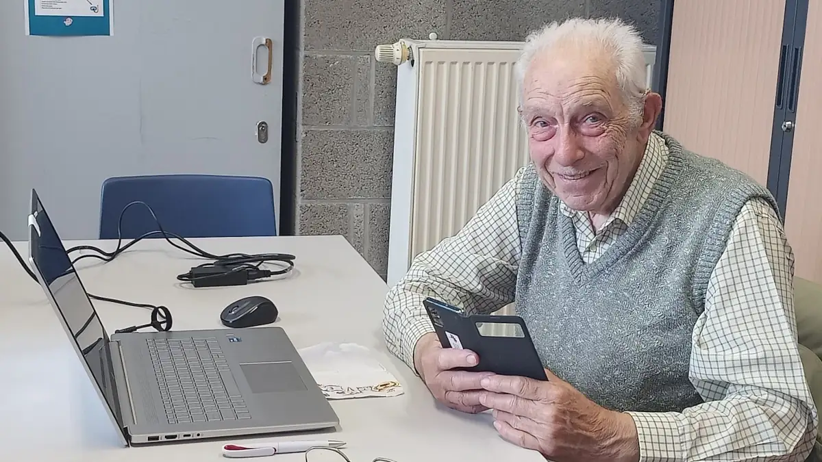 Senior participant à un atelier de sécurité informatique, apprenant à utiliser un smartphone et un ordinateur pour adopter de bons réflexes numériques.